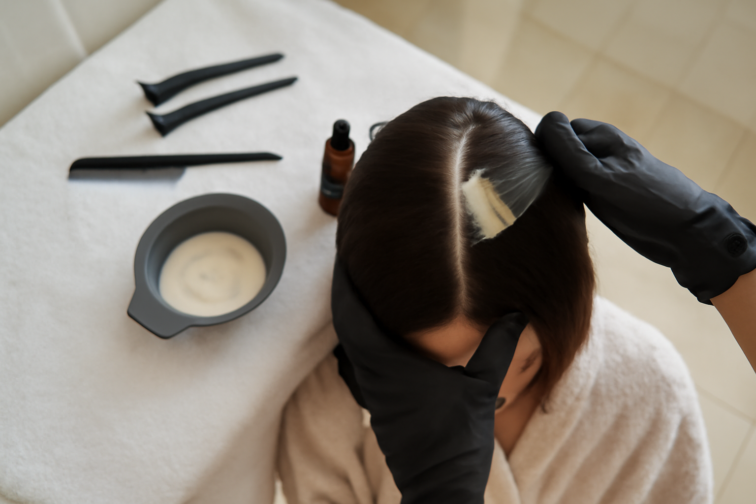 Massage du cuir chevelu avec un mélange d’huile de romarin cheveux diluée, pinces à cheveux et peigne sur serviette